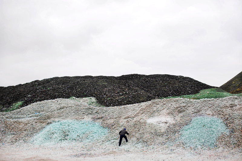 A worker collects plastic bottles.